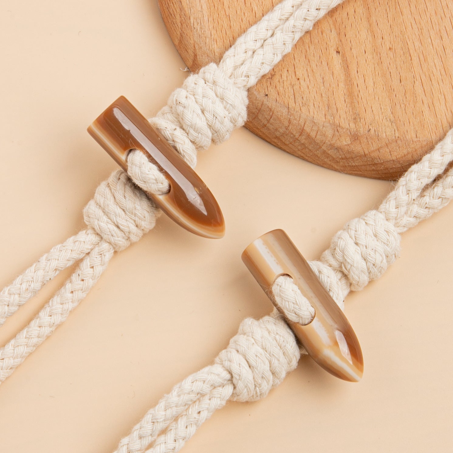 Beige cord coat buckle pair with resin horn tips and loop knots for fastening