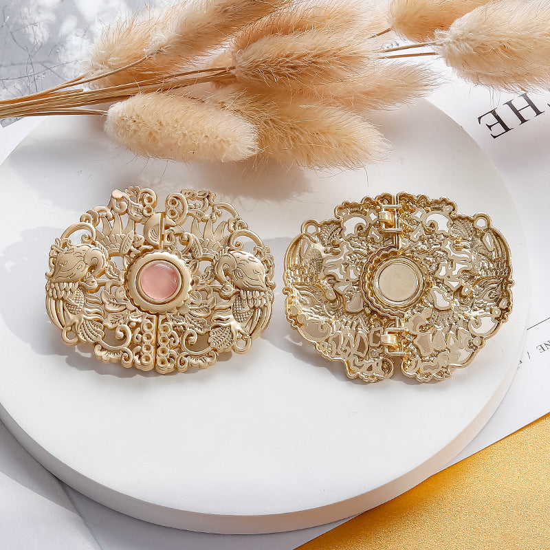Pair of golden ornate phoenix hook buttons with round pink center, decorative filigree