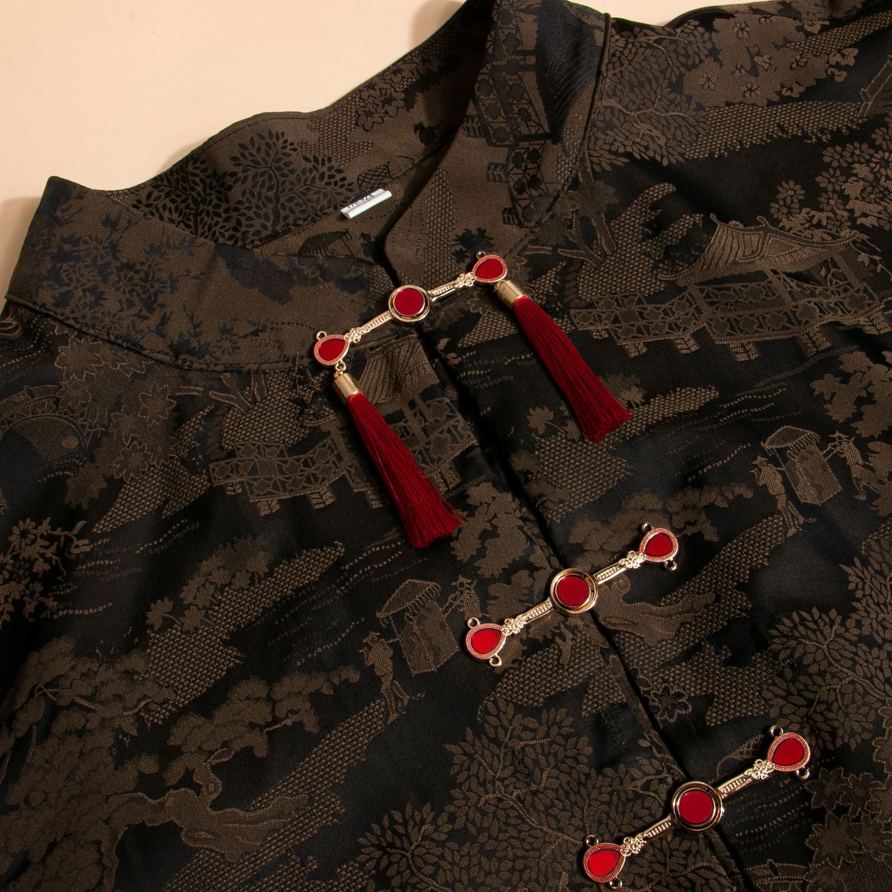 Gold-tone Chinese frog buttons with red tassels on dark patterned hanfu