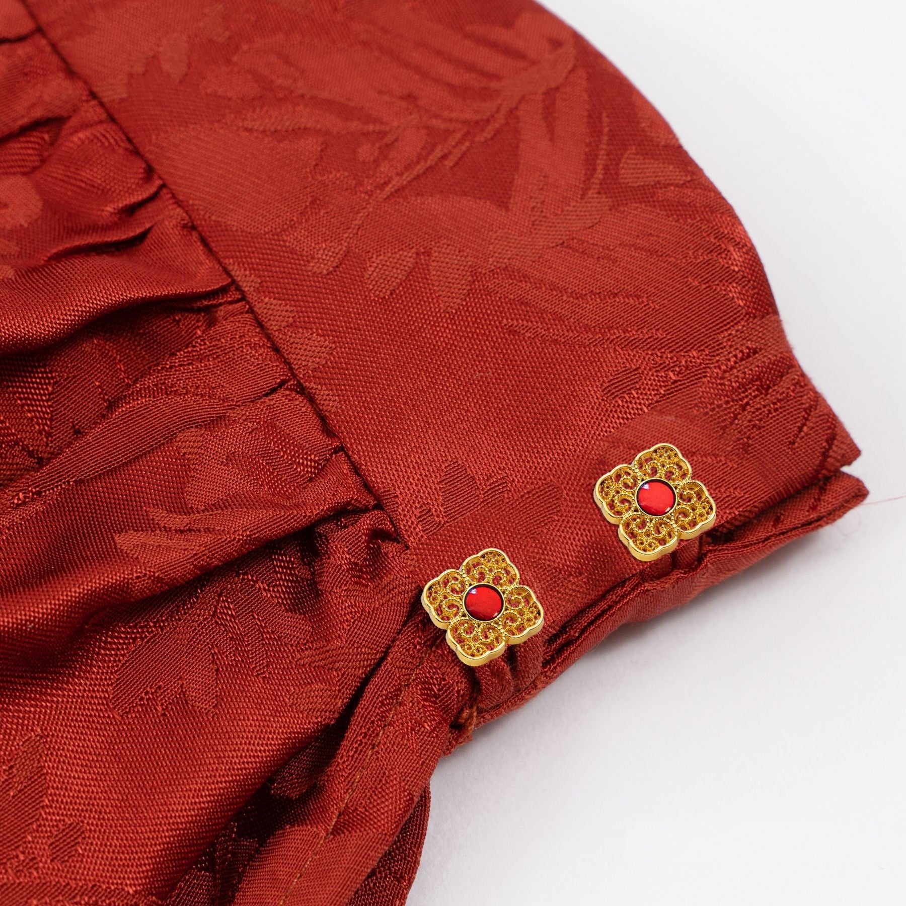 Square metal buttons on red fabric: gold filigree with red round centers