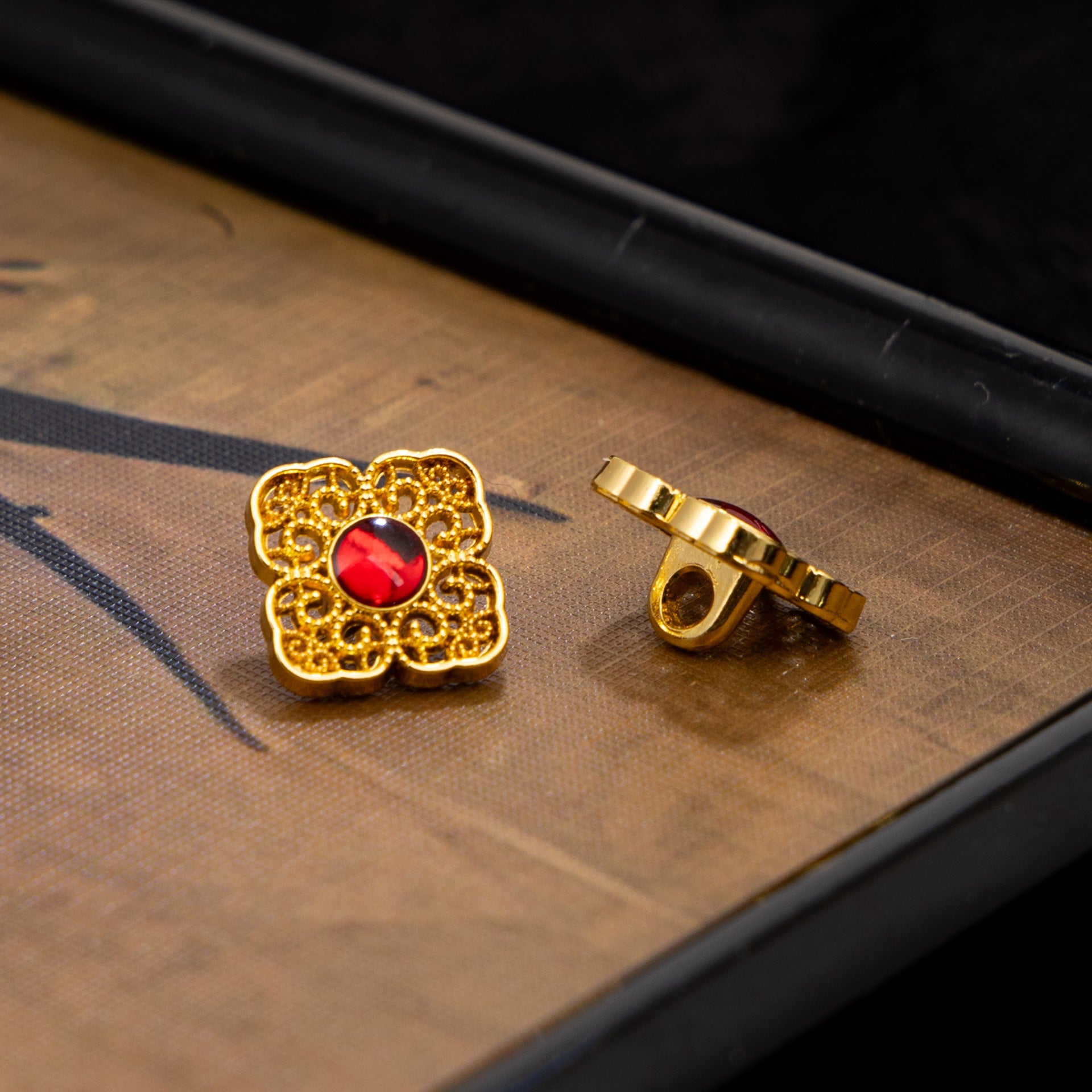 Gold square button with red round center and metal back, ornate filigree