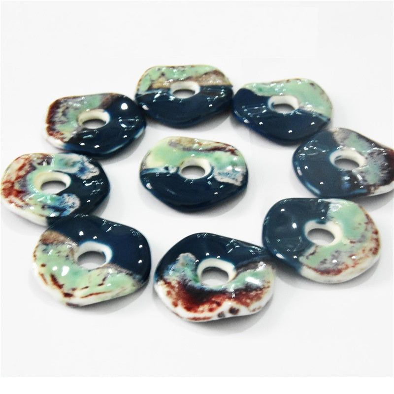 Mixed set of 40mm round ceramic ornament pendants, green-speckled top over dark blue with hole.