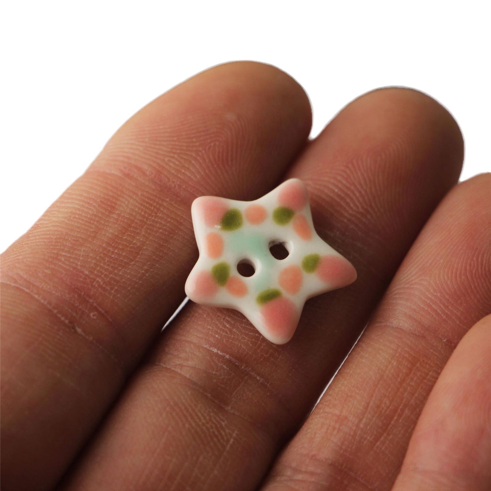 Pastel ceramic five-point star button with two holes, orange and green speckles