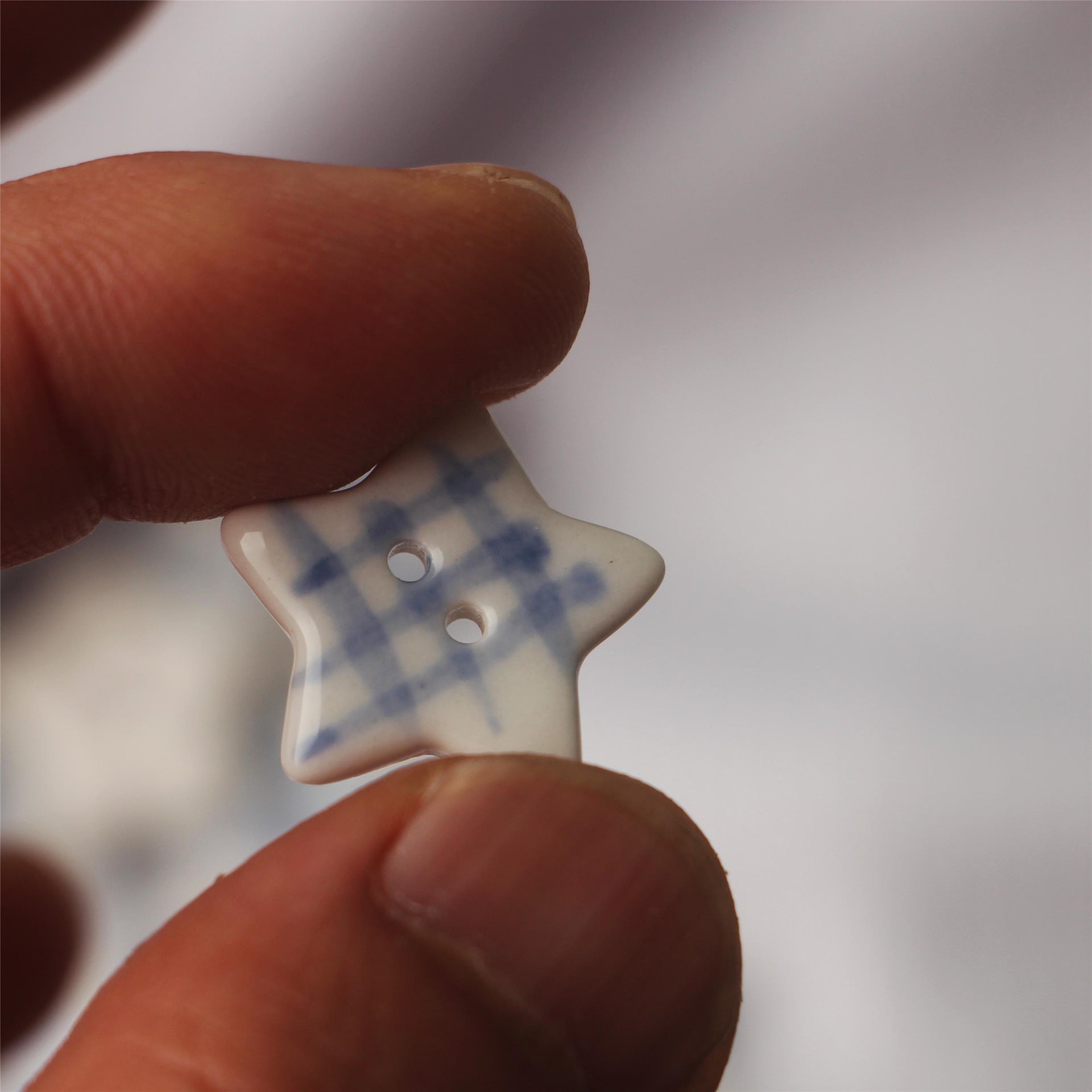 Close-up of a five-point star ceramic button showing two holes and blue print