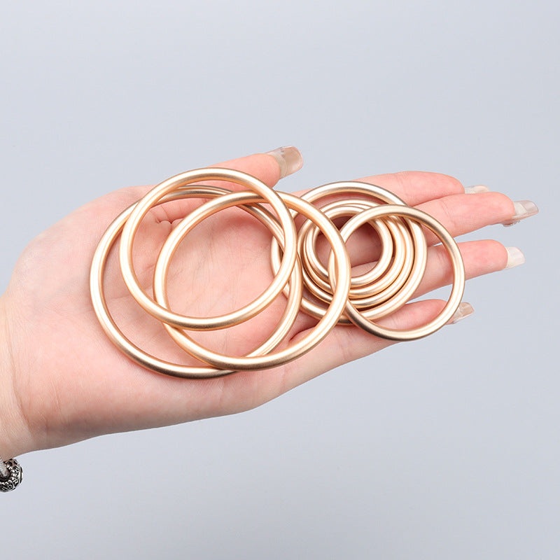 Mehrere goldfarbene Metallringe für Gurtband in der Hand, 20–45 mm