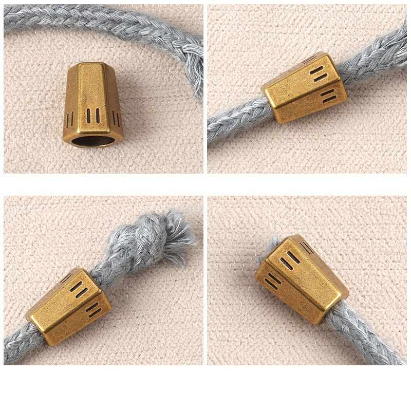 Gold-toned cord end stopper on gray braided cord with rectangular vent cutouts
