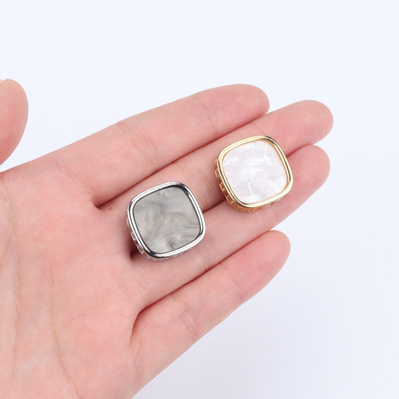 Gold and silver square metal shank buttons on hand, 21mm