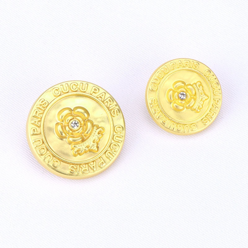 Gold round metal shank button with rhinestone flower emblem and CUCU PARIS rim text