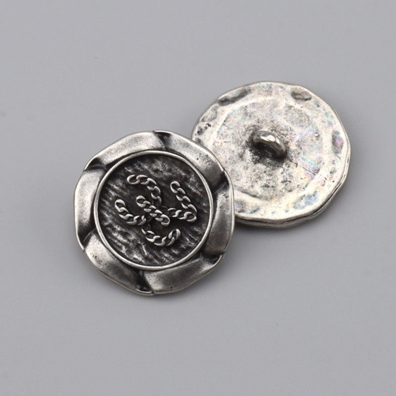 Dark silver metal button with shank back, ornate engraved front