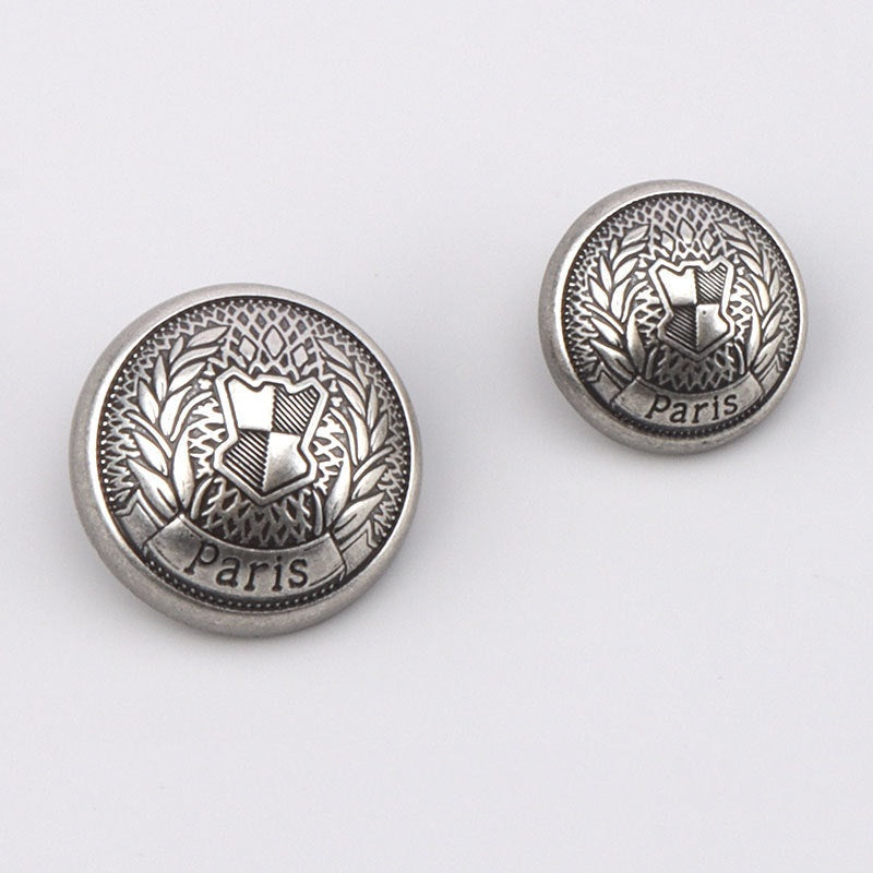 Two round silver metal buttons with Paris text, laurel crest design, metal shanks