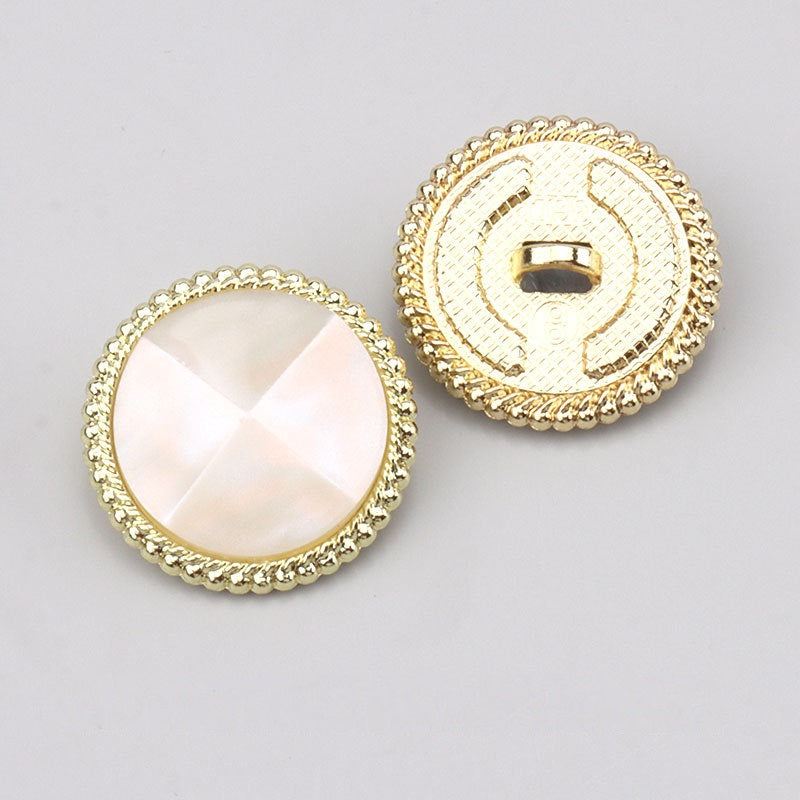 White faceted resin button front and back view with gold-tone rim and metal shank