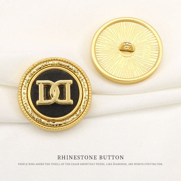 Round gold rhinestone shank button with black center and DD letter pattern, close-up
