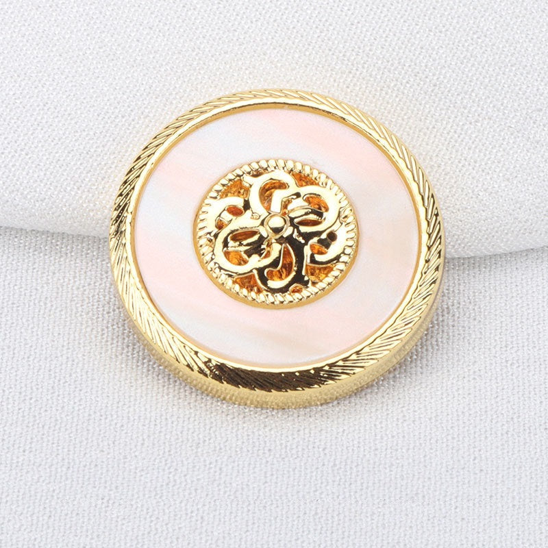 Gold resin metal button with decorative floral emblem and ridged rim, close-up