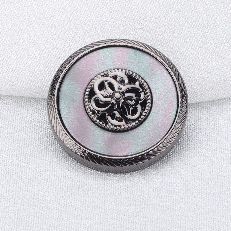 Gunmetal resin metal button with ornate floral emblem and etched border, close-up