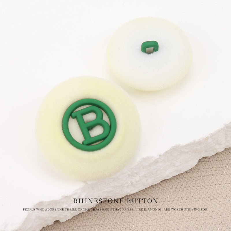 Flocked round “B” buttons with shank, cream base with green letter “B”