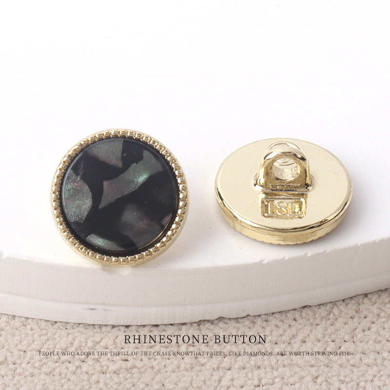 Black resin-look 11mm button with gold rim and faceted pearl-like surface