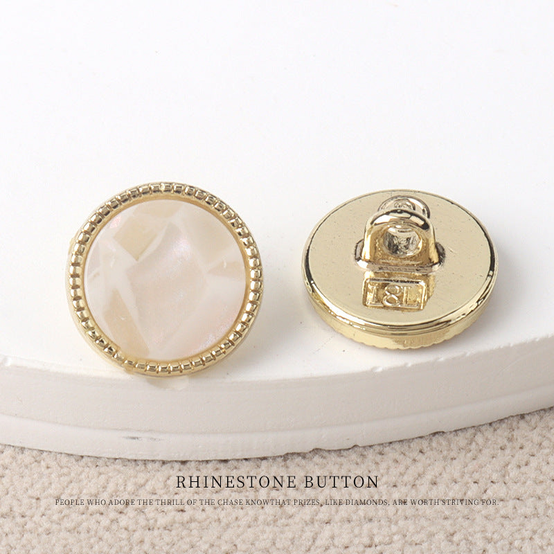 White resin-look 11mm button, shown from front and gold metal shank back