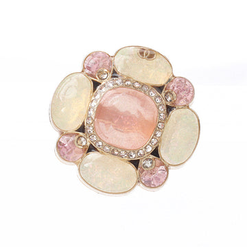 Botón floral de pedrería con centro rosa translúcido y pétalos claros, montura dorada
