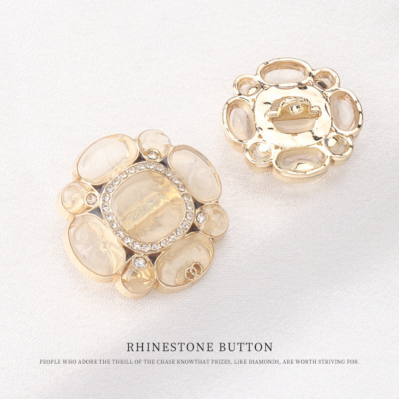 Botón floral de pedrería con pétalos transparentes y centro claro, tono dorado