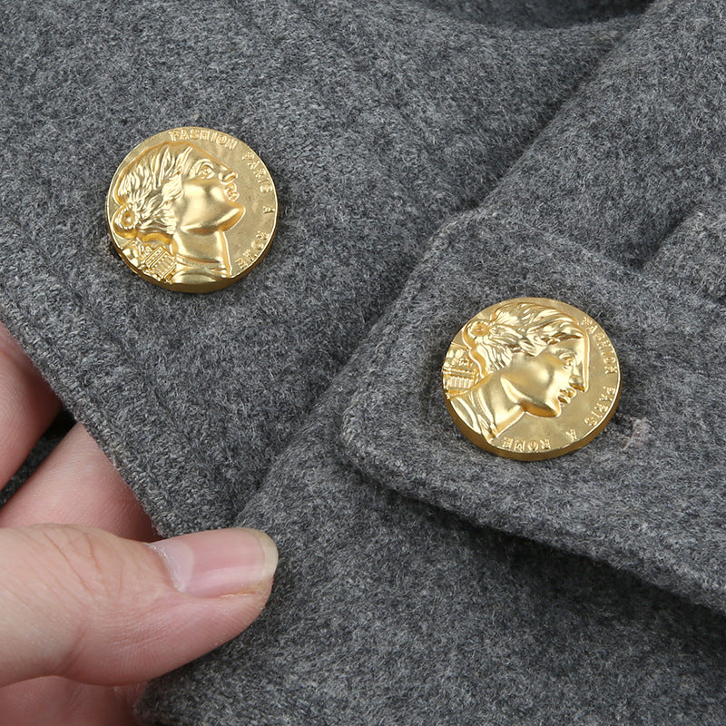 Gold-tone Roman head metal shank button on dark fabric, round black shank base