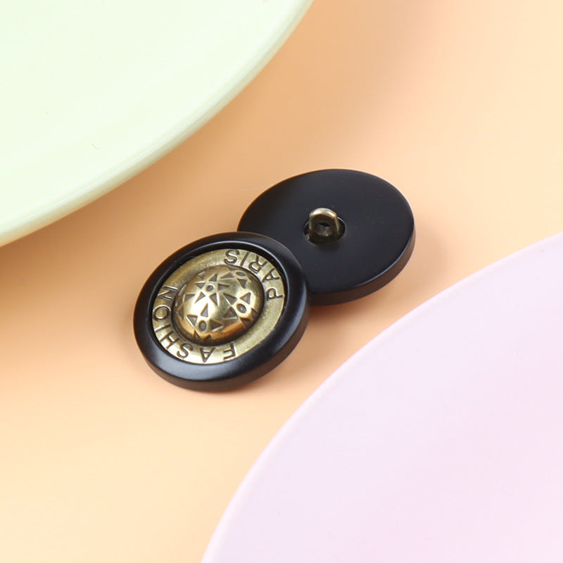 Metal shank button with scarab-like circular emblem, black back and gold-tone front