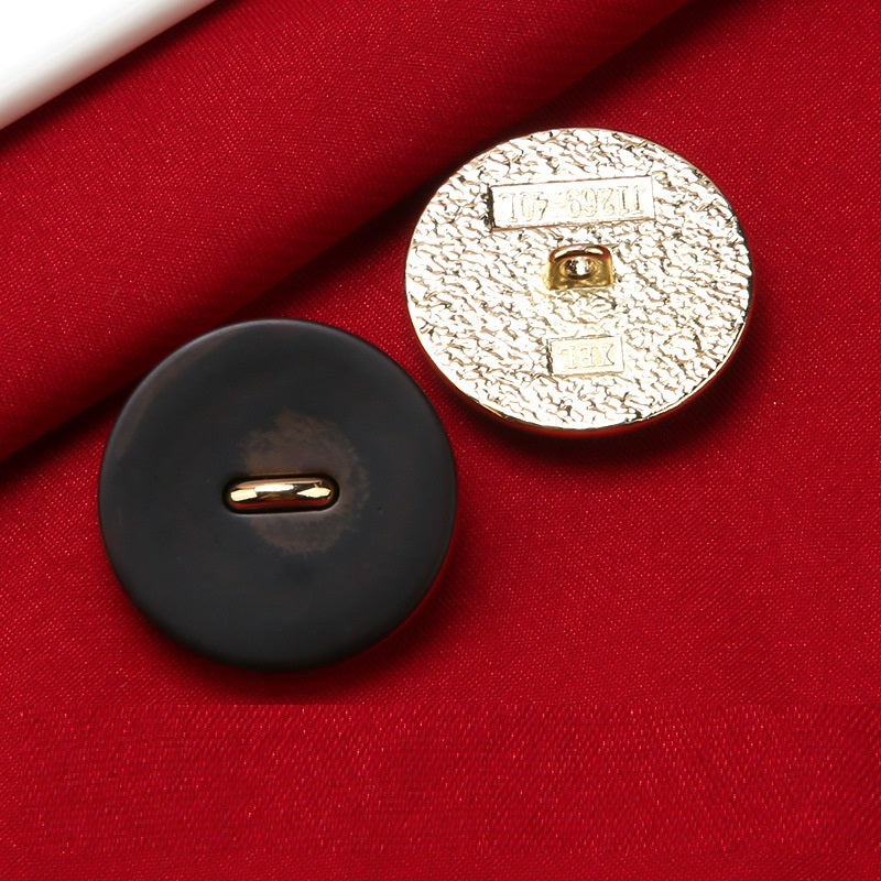 Schwarzer Harz-Mantelknopf mit goldfarbener Schaftöse und Metallrückseite mit Prägung