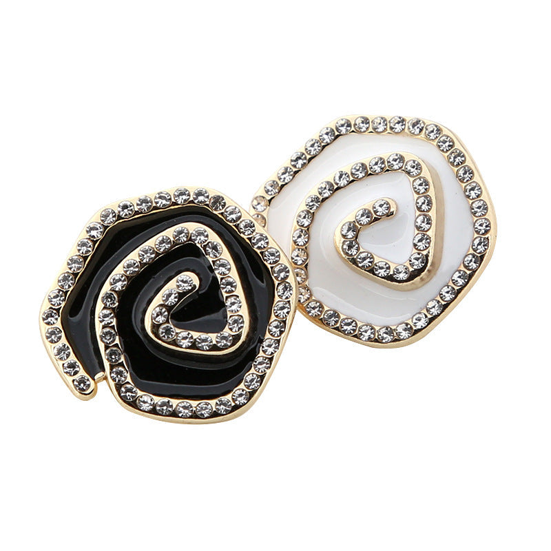 Irregular curved metal buttons set with rhinestones, one black and one white, gold-tone edges