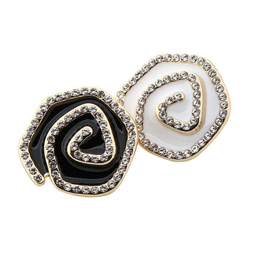 Irregular curved metal buttons set with rhinestones, one black and one white, gold-tone edges