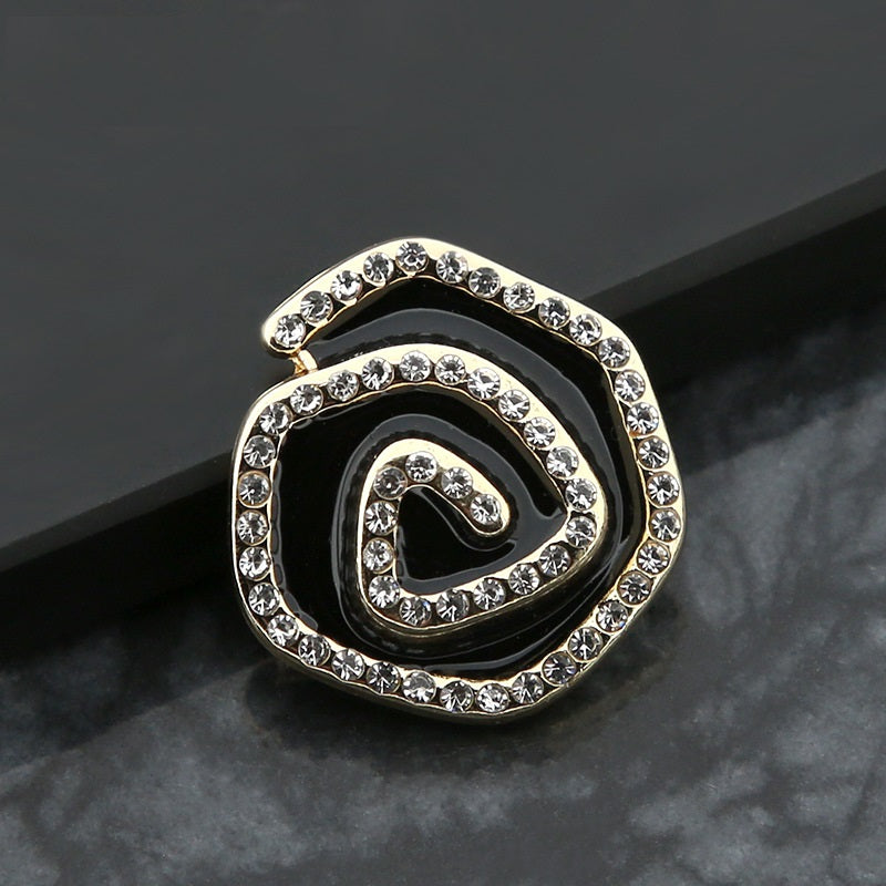 Curved metal button with rhinestones and swirl design, black enamel center, gold-tone frame