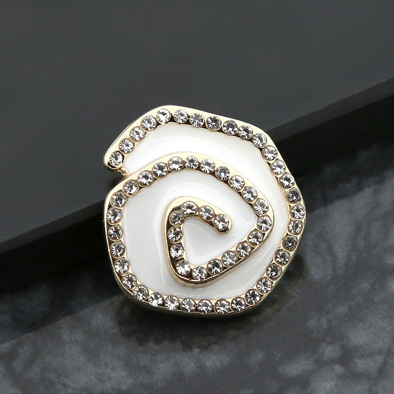 Curved metal button with rhinestones and swirl design, white enamel center, gold-tone frame