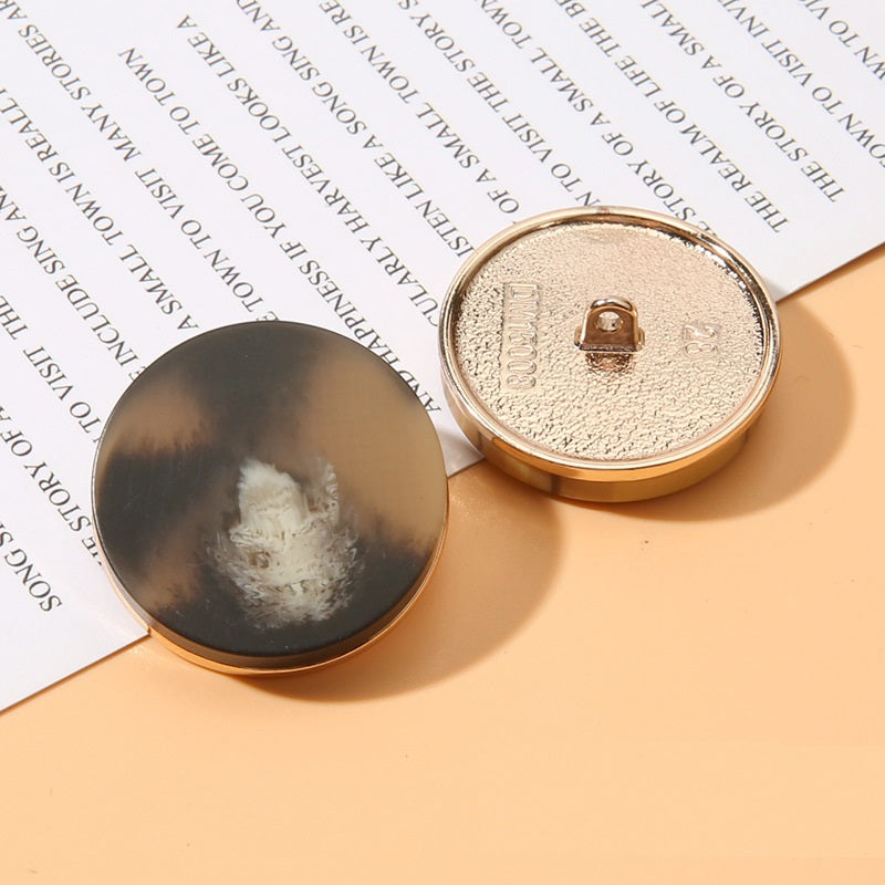 Dark round resin shank button front with beige metal back, gold rim