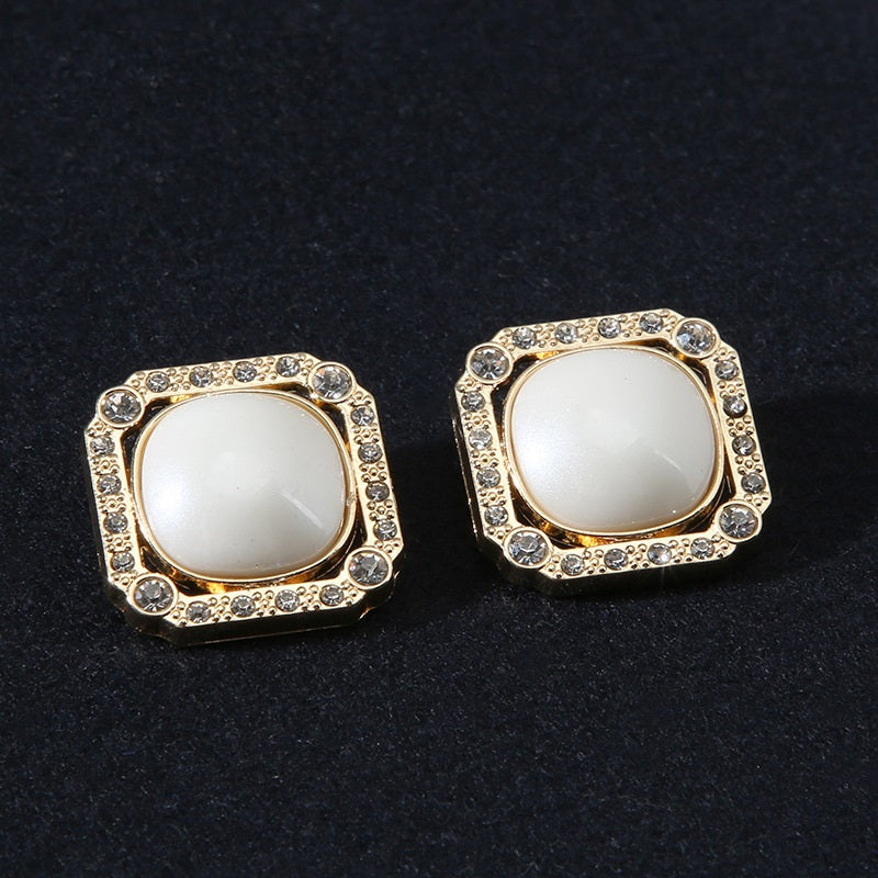 Pair of gold-tone square shank buttons with rhinestone border and pearl-look center