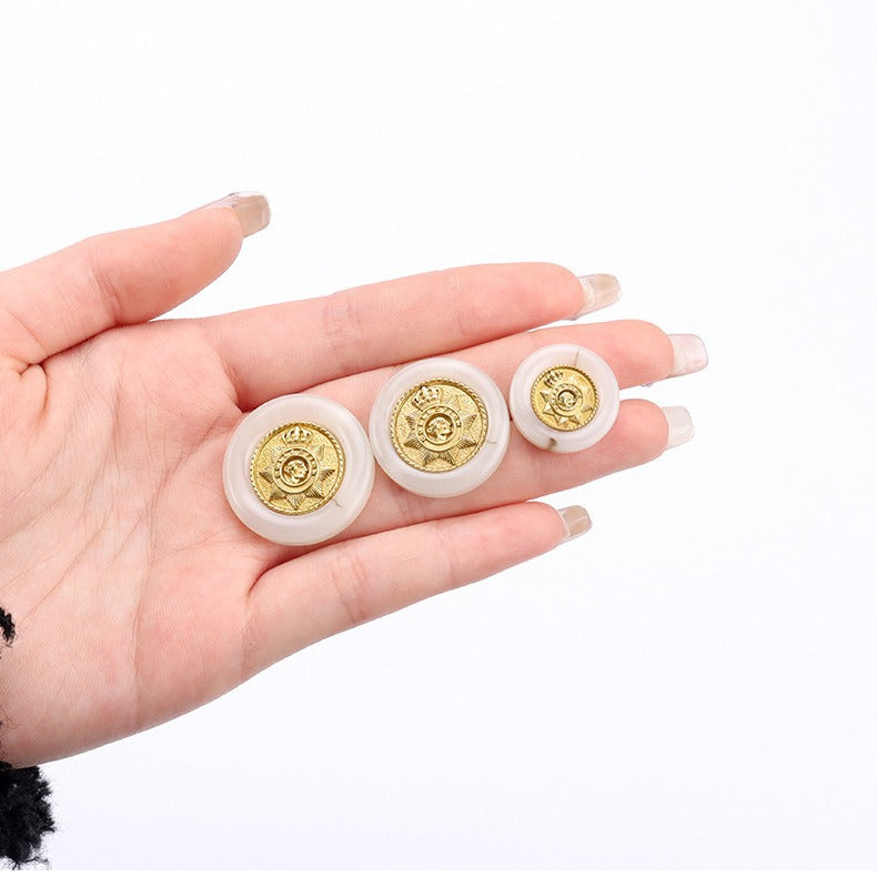 White round resin buttons with gold crown star crest, held in a hand