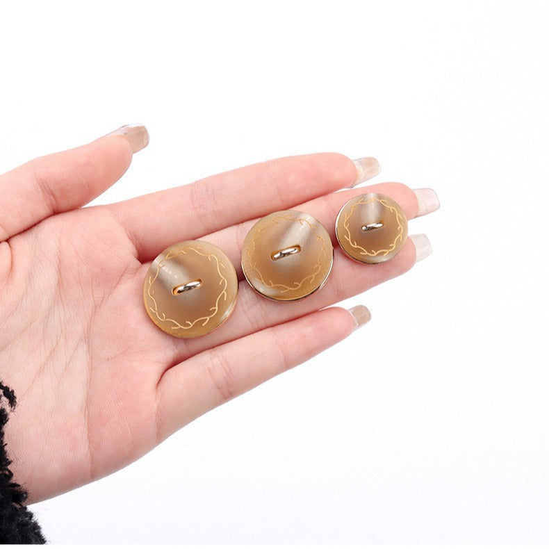 18–25mm round shank buttons in khaki, gold-tone accents, held in hand