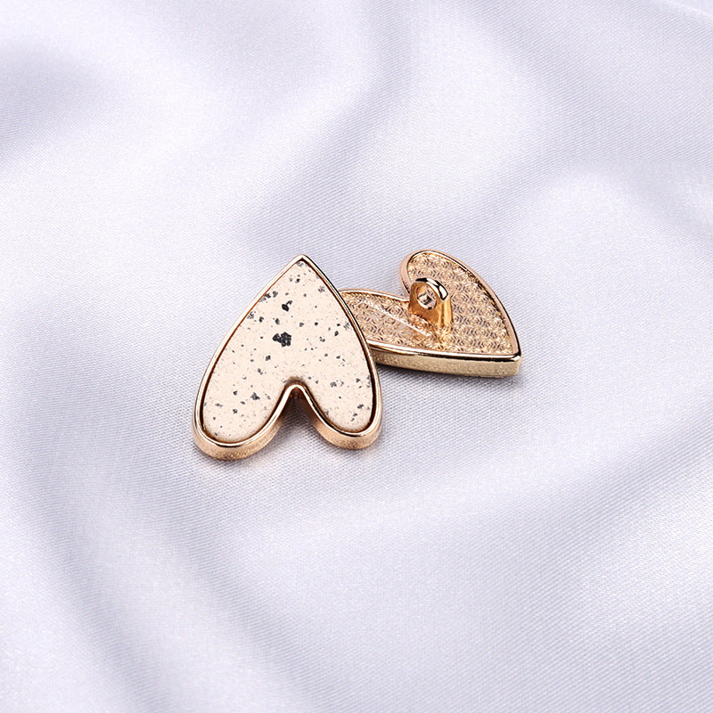 Heart-shaped metal shank button, beige speckled front with gold-tone edges