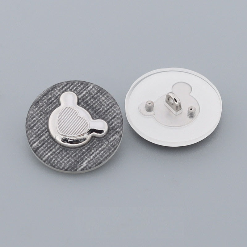 Round bear-shaped metal buttons, front and reverse view with shank pins visible