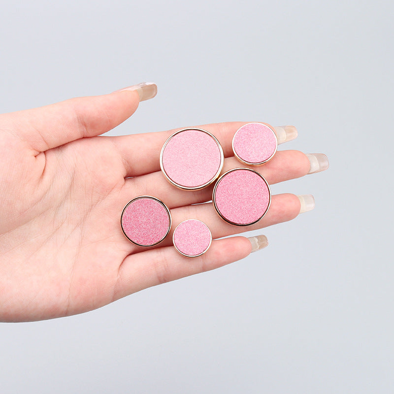 Pink round recycled resin buttons with metal bases in hand, mixed sizes