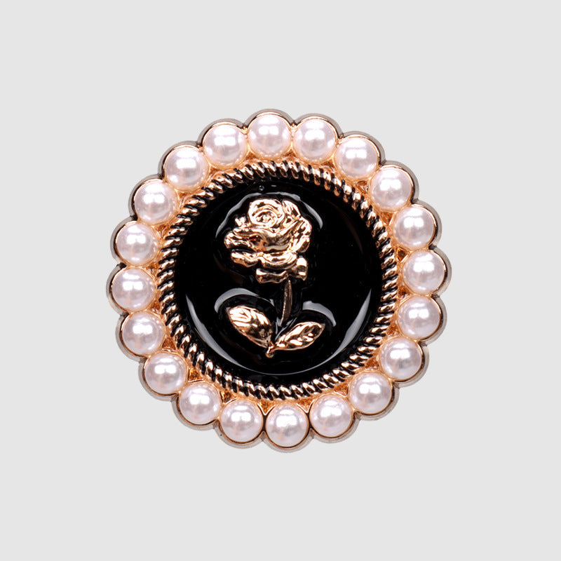 Close-up of pearl rose metal button with black center, gold rose motif