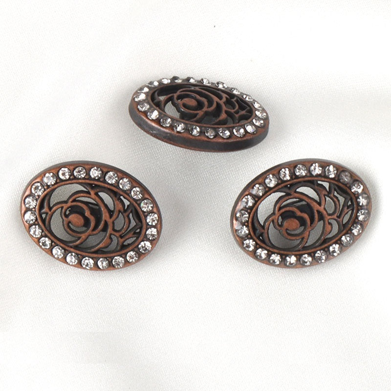 Three oval rhinestone buttons with bronze-red filigree rose centers and clear stones