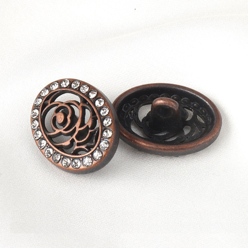 Bronze-red oval button with shank; floral filigree and clear rhinestone ring