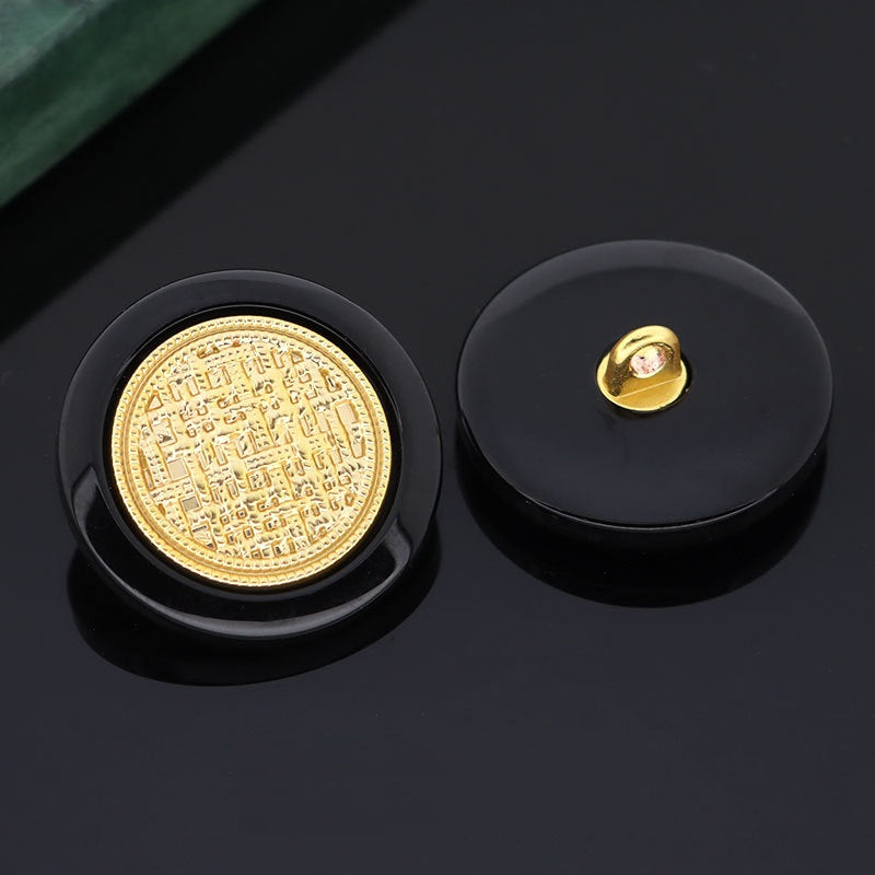 Schwarzer Knopf mit goldener Metallöse auf Rückseite