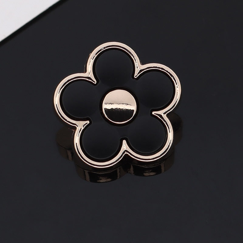 Black floral shaped metal shank button with silver outline and light center