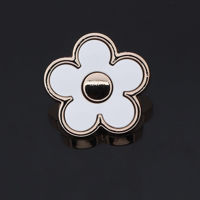 White floral shaped metal shank button with silver outline and dark center