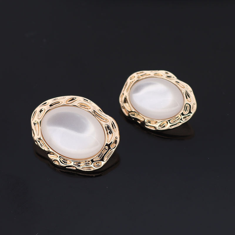 White resin button pair with gold-tone metal shank and ornate oval border