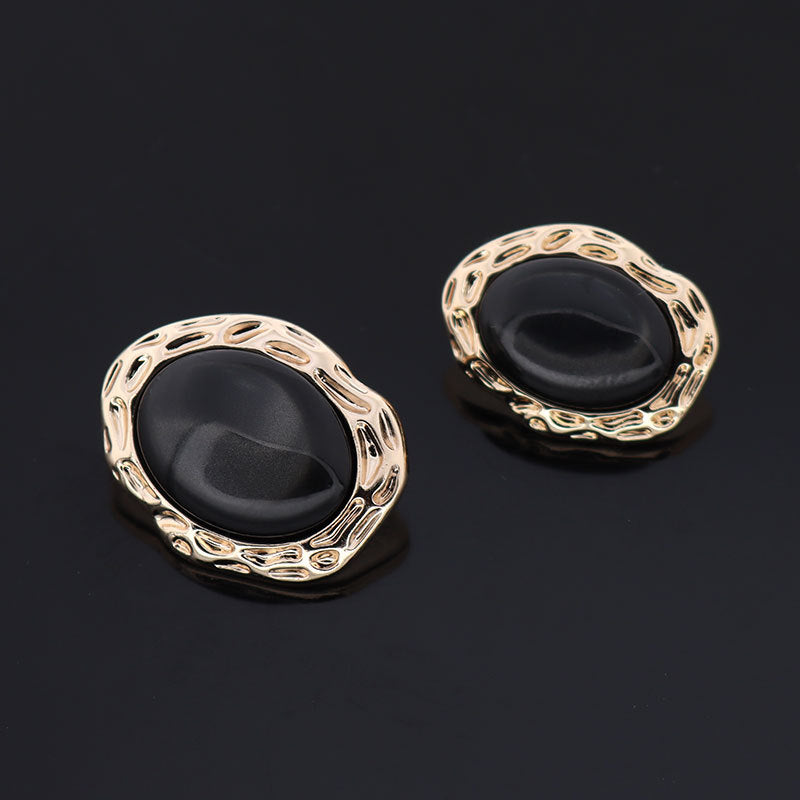 Black resin button pair with gold-tone metal shank and ornate oval border