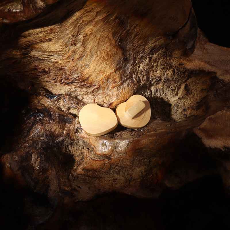 Two heart-shaped natural wooden coat buttons on wood grain, 15mm with shanks