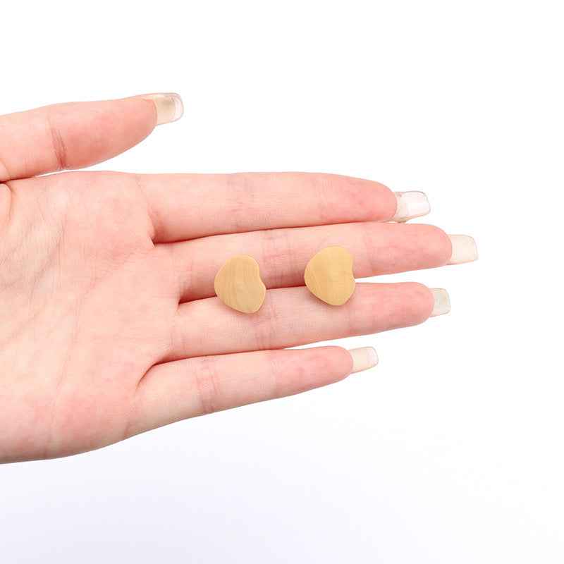 Heart-shaped natural wooden buttons with shanks held in hand, 15mm