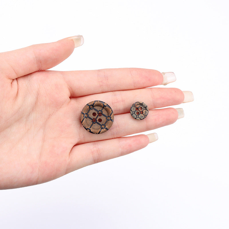 Two round 4-hole navy wood buttons with laser-carved vintage design in hand
