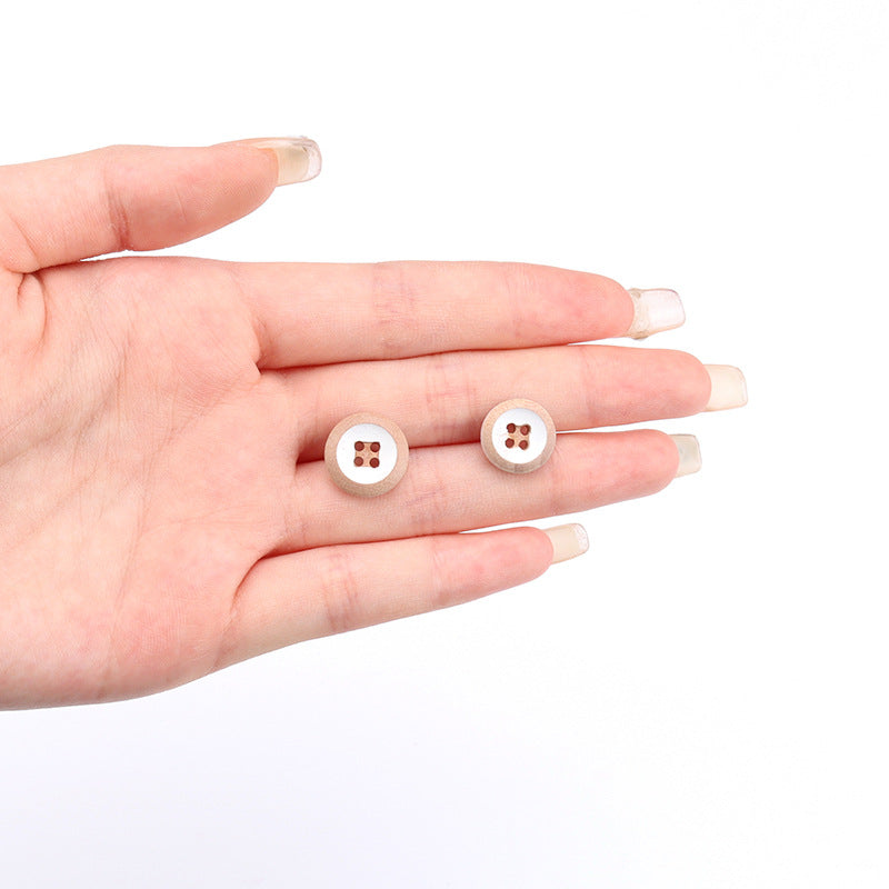 Two 4-hole round wooden buttons held in hand, yellow and white faces