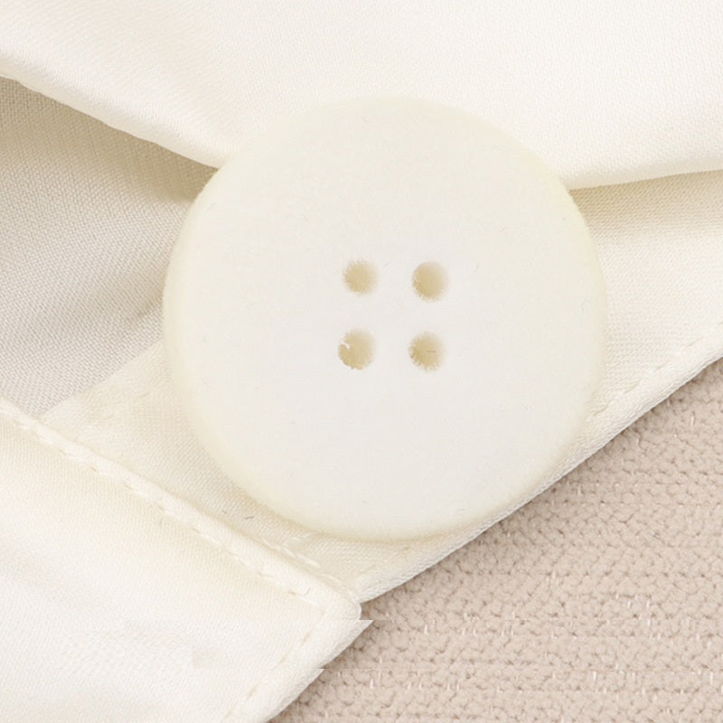 White flocked flat button with four holes, 15–25mm, close-up on fabric